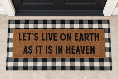 XL Doormat | Let's Live on Earth as It Is in Heaven layered over a black and ivory buffalo plaid runner at a black door.