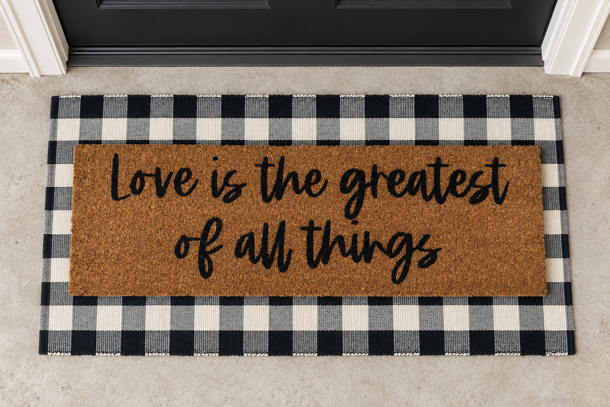 XL Doormat | Love Is the Greatest of All Things layered over a black and ivory buffalo plaid runner at a black door.