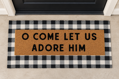 XL Christian Doormat | O Come Let Us Adore Him layered over a black and ivory buffalo plaid runner at a black door.