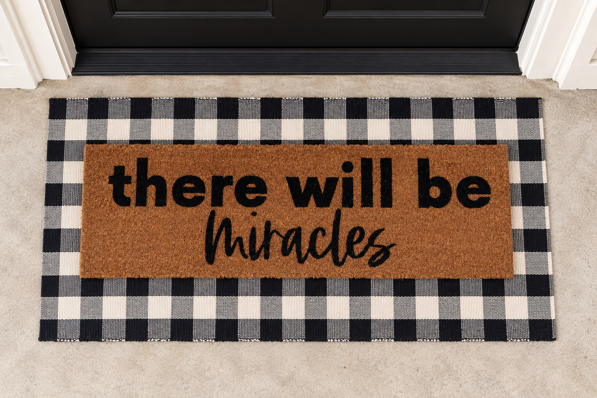 XL Doormat | There Will Be Miracles layered over a black and ivory buffalo plaid runner at a black door.