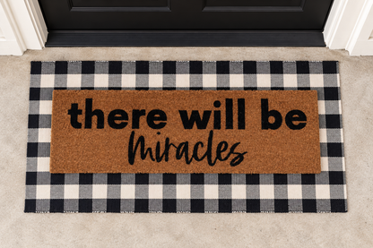 XL Doormat | There Will Be Miracles layered over a black and ivory buffalo plaid runner at a black door.