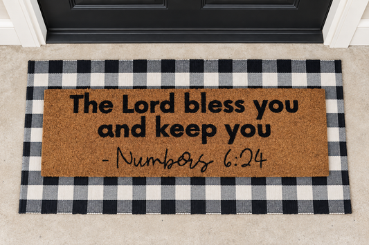 XL Scripture Doormat | Numbers 6:24 layered over a black and ivory buffalo plaid runner at a black door.