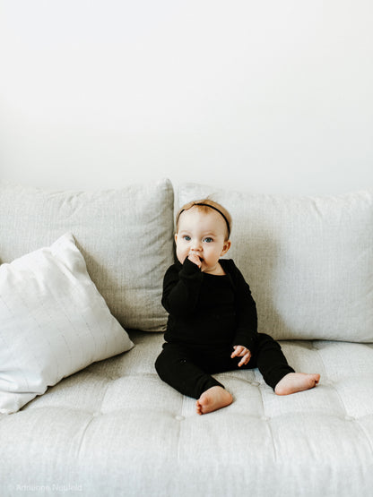 Organic Baby + Kids Pajama Set | Black — Baby seated in black pajamas