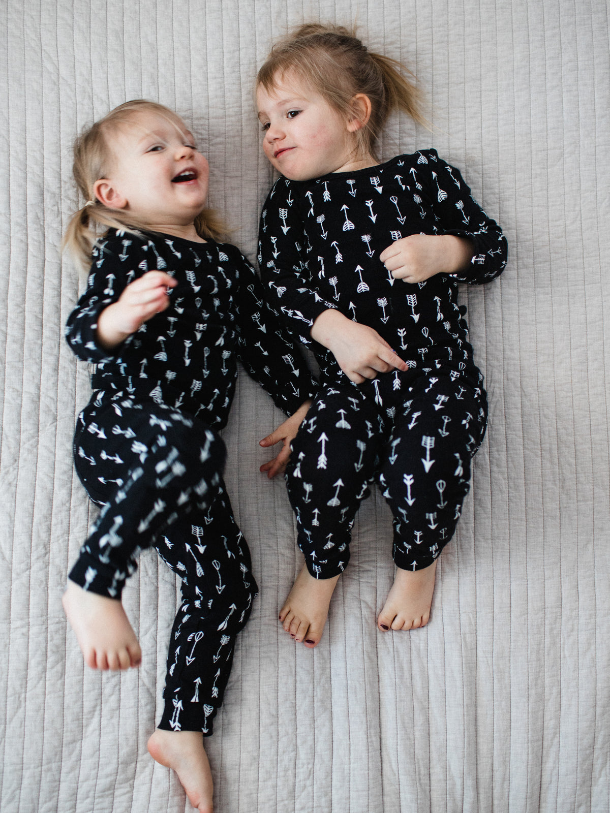 Organic Baby + Kids Pajama Set | White on Black Arrows — Children reclining in matching arrow pajamas
