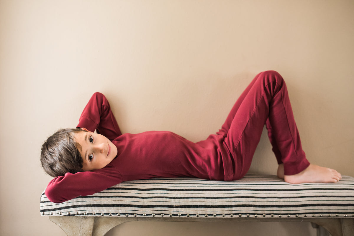 Organic Baby + Kids Pajama Set | Maroon — Child reclining in the full pajama set
