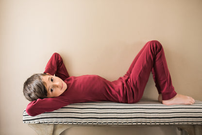 Organic Baby + Kids Pajama Set | Maroon — Child reclining in the full pajama set