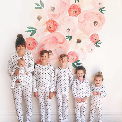 Organic Baby + Kids Pajama Set | Black on White Snowflakes — Children wearing snowflake pajamas against a floral backdrop