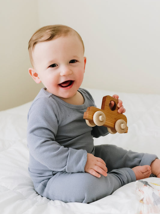 Child seated on a bed wearing Tradewinds thermal pajamas