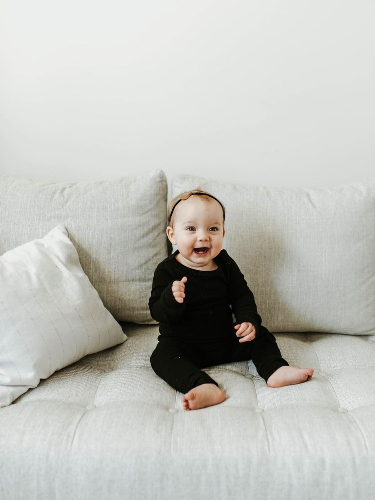 Organic Baby + Kids Pajama Set | Black — Baby wearing black pajamas on a couch