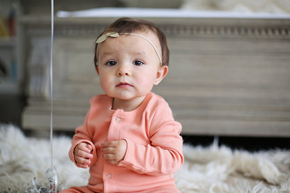 Close view of a baby wearing a peach button coverall