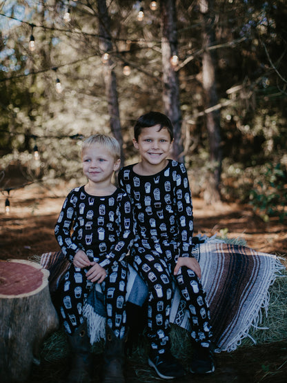 Organic Baby + Kids Pajama Set | White on Black Coffee Love — Children seated outdoors in matching printed pajamas