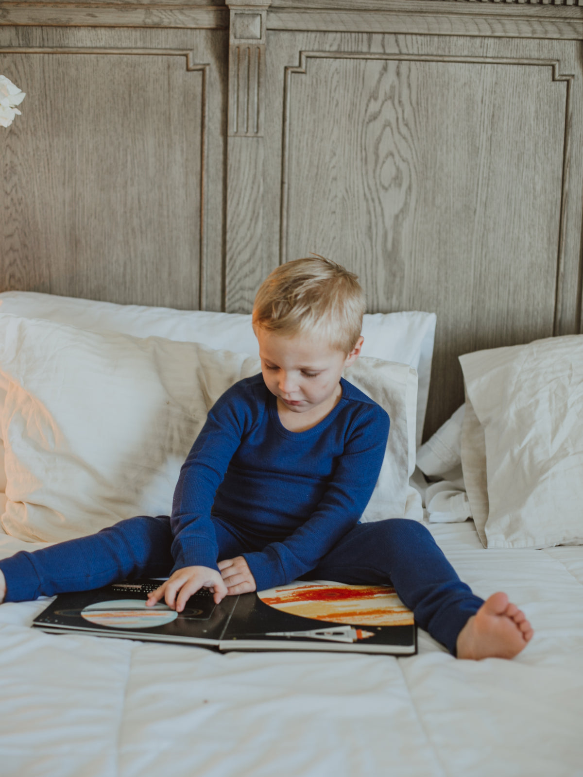 Organic Thermal Baby + Kids Pajama Set | Navy Peony — Child reading in navy thermal pajamas