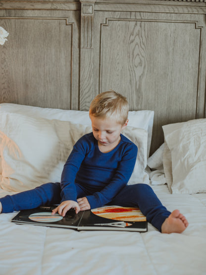 Organic Thermal Baby + Kids Pajama Set | Navy Peony — Child reading in navy thermal pajamas