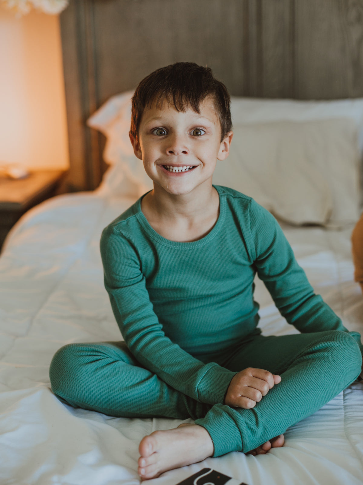 Organic Thermal Baby + Kids Pajama Set | Pine Green — Child seated in the full green pajama set