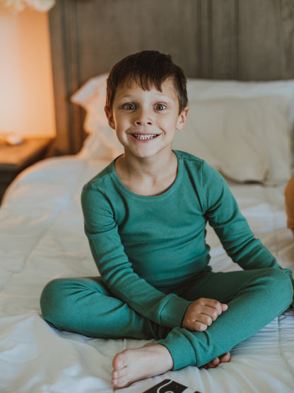 Organic Thermal Baby + Kids Pajama Set | Pine Green — Child seated in the full green pajama set