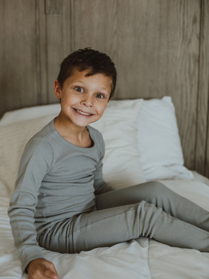 Organic Thermal Baby + Kids Pajama Set | Neutral Gray — Child seated in the full gray pajama set