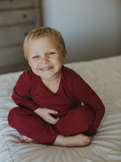 Organic Thermal Baby + Kids Pajama Set | Maroon — Child seated in maroon thermal pajamas