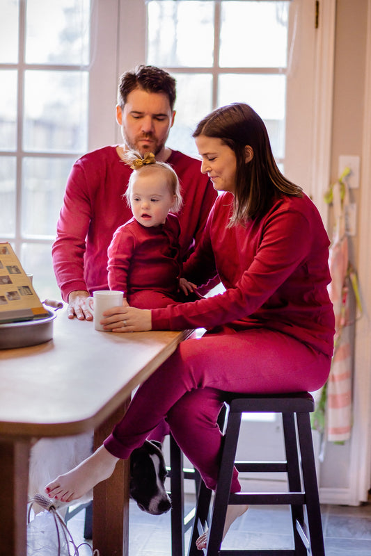 Family wearing maroon pajamas seated at a kitchen table