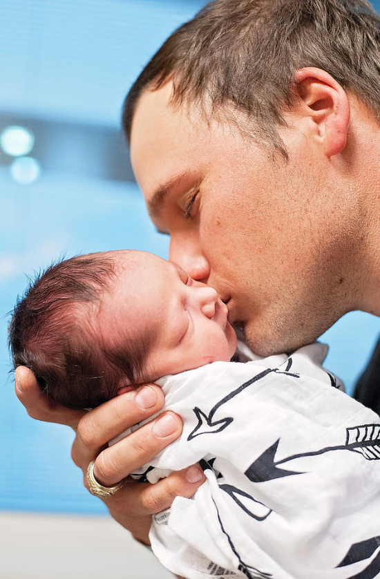 Parent pictured with baby and Arrows Organic Swaddle.