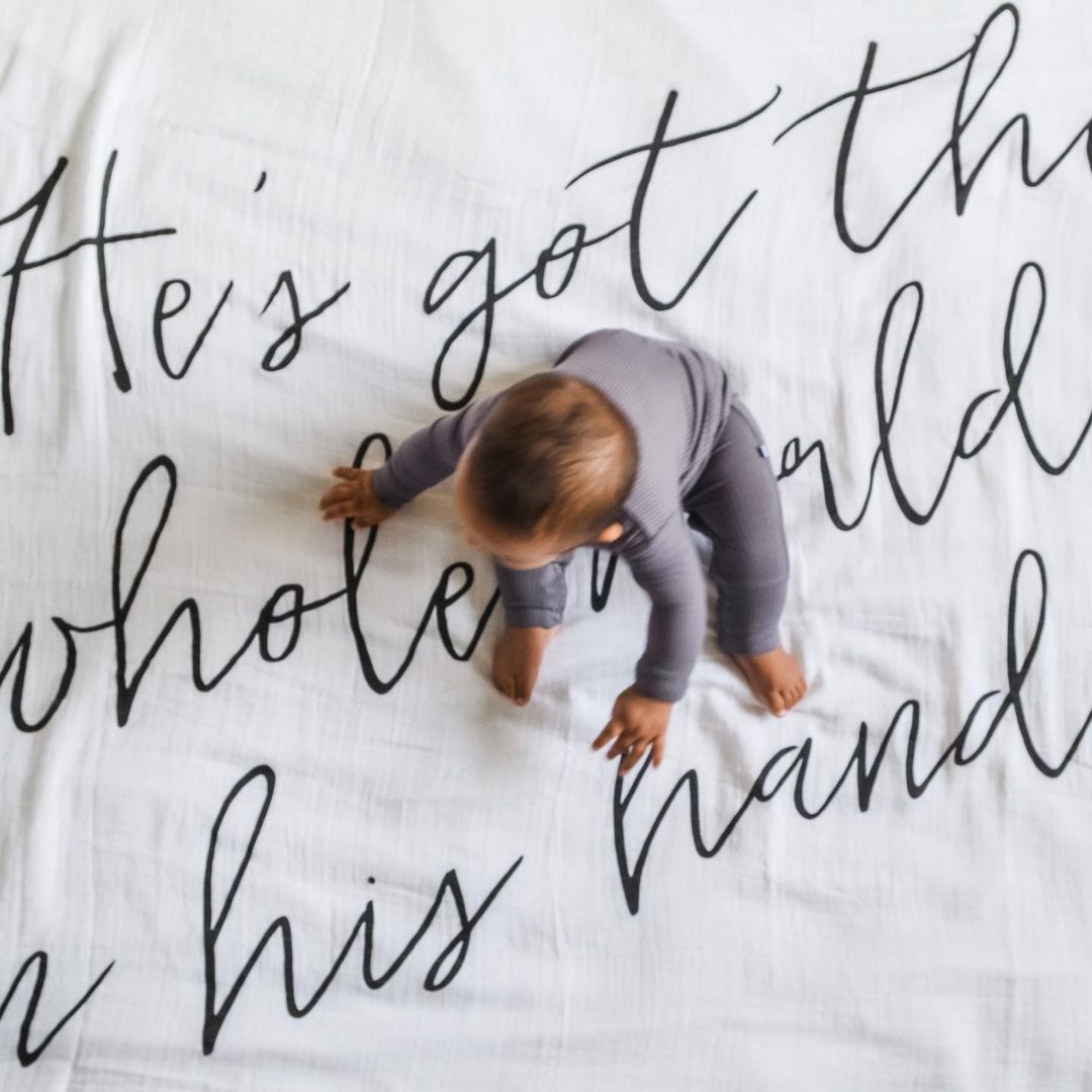 A baby lying on a black and white swaddle blanket with text design