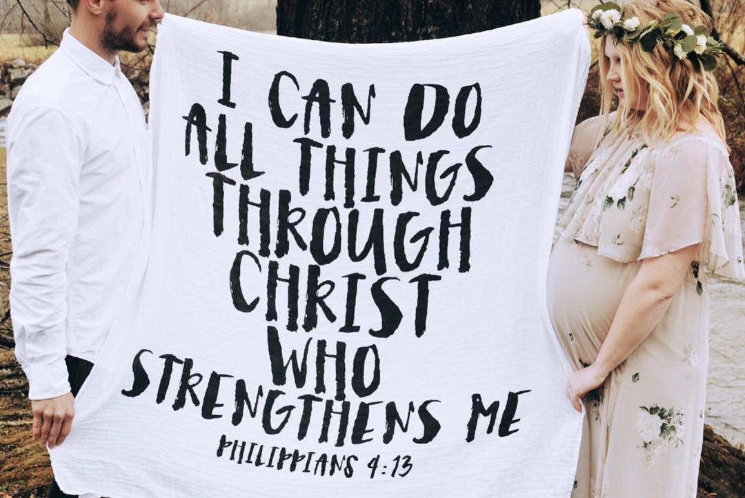 Family holding up Philippians 4:13 Scripture Swaddle.