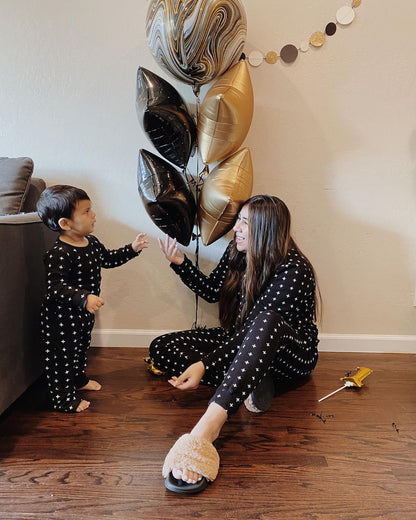 Organic Baby + Kids Pajama Set | White on Black Swiss Cross — Parent and child wearing Swiss Cross pajamas beside balloons