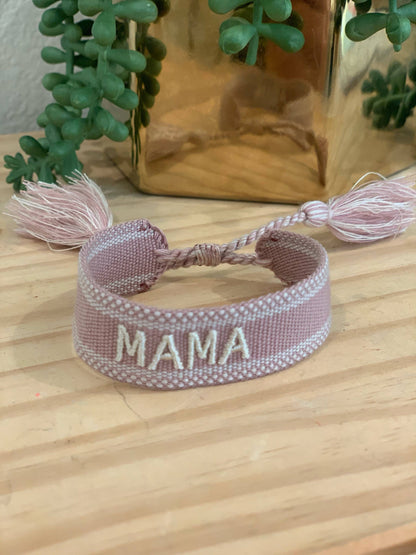 Pale pink woven MAMA bracelet with light embroidered lettering and tassel ends.