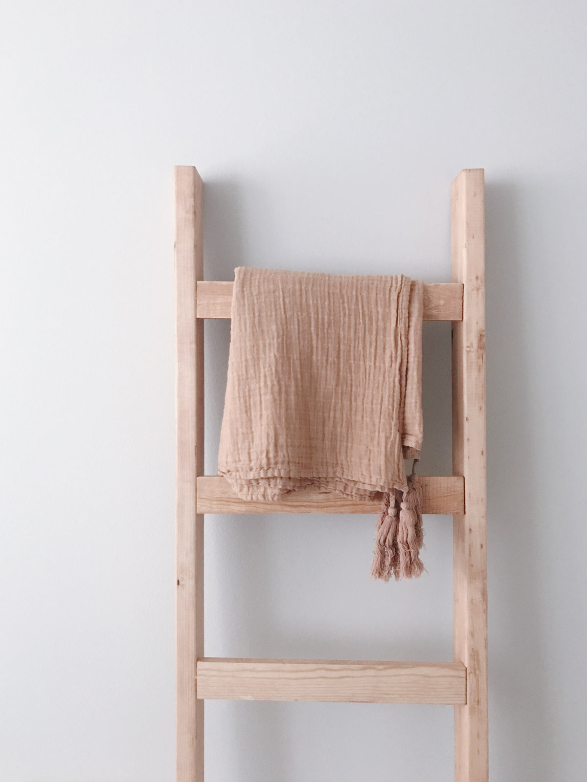 Ginger tassel muslin throw draped over a wooden blanket ladder