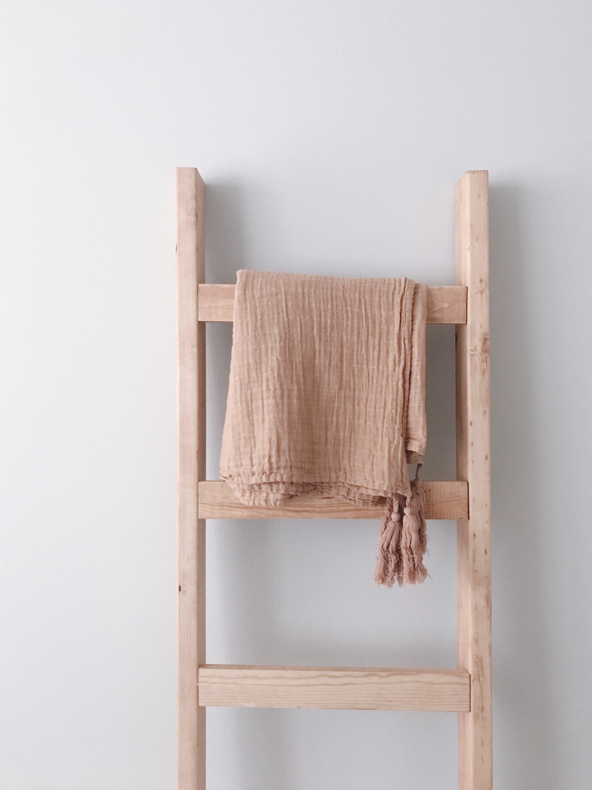 Ginger tassel muslin throw draped over a wooden blanket ladder