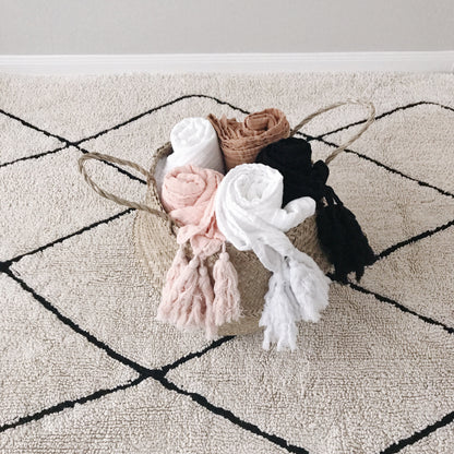 Muslin tassel throw color assortment in a woven basket