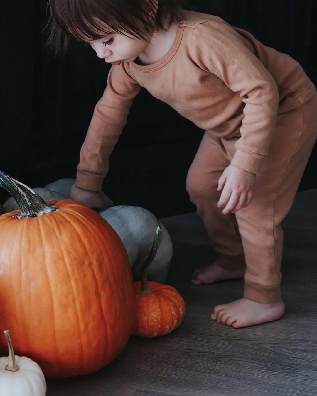 Organic Baby + Kids Pajama Set | Ginger — Child wearing the set standing beside a pumpkin