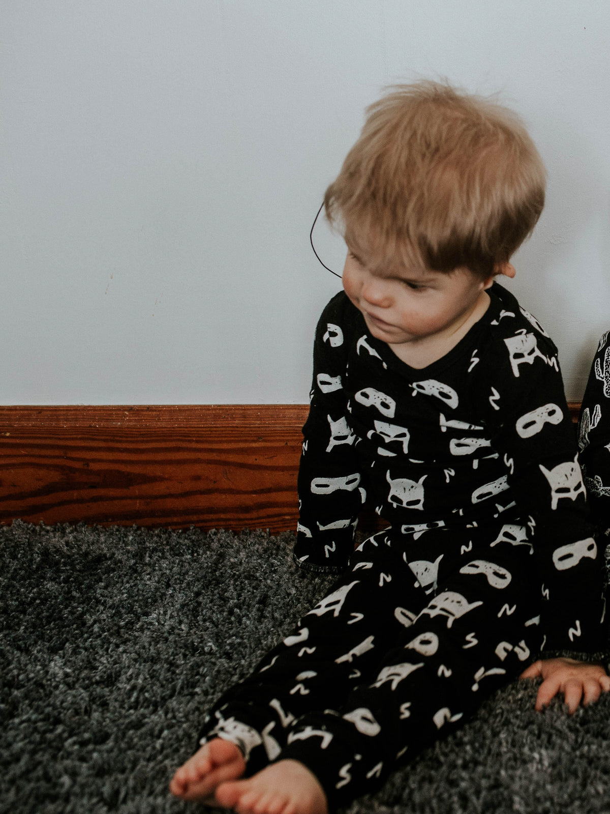Organic Baby + Kids Pajama Set | White on Black Hero Struck — Child seated in the printed pajamas