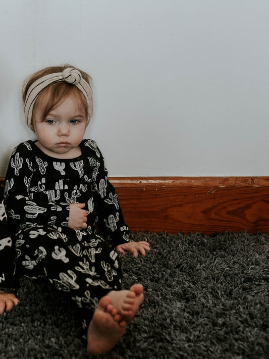Child wearing a black pajama set with white cactus prints